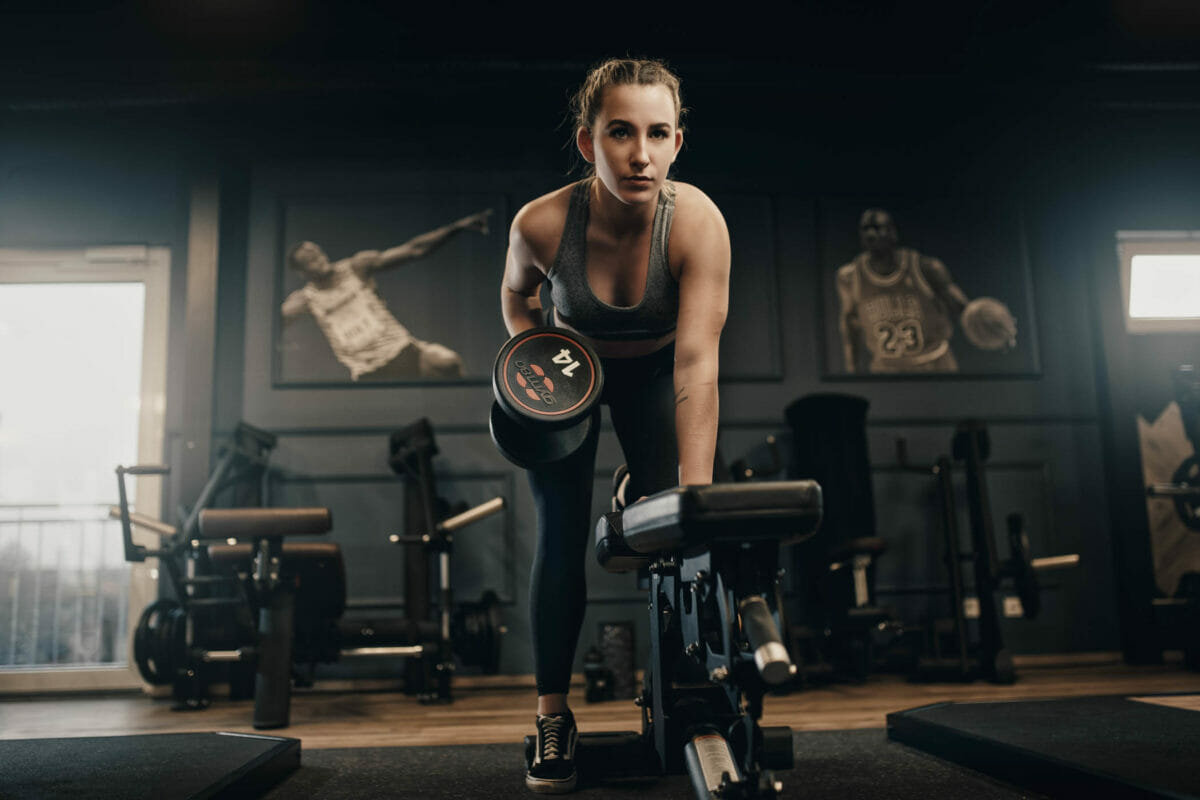 Sportlerin trainiert mit Kurzhantel im Fitnessstudio