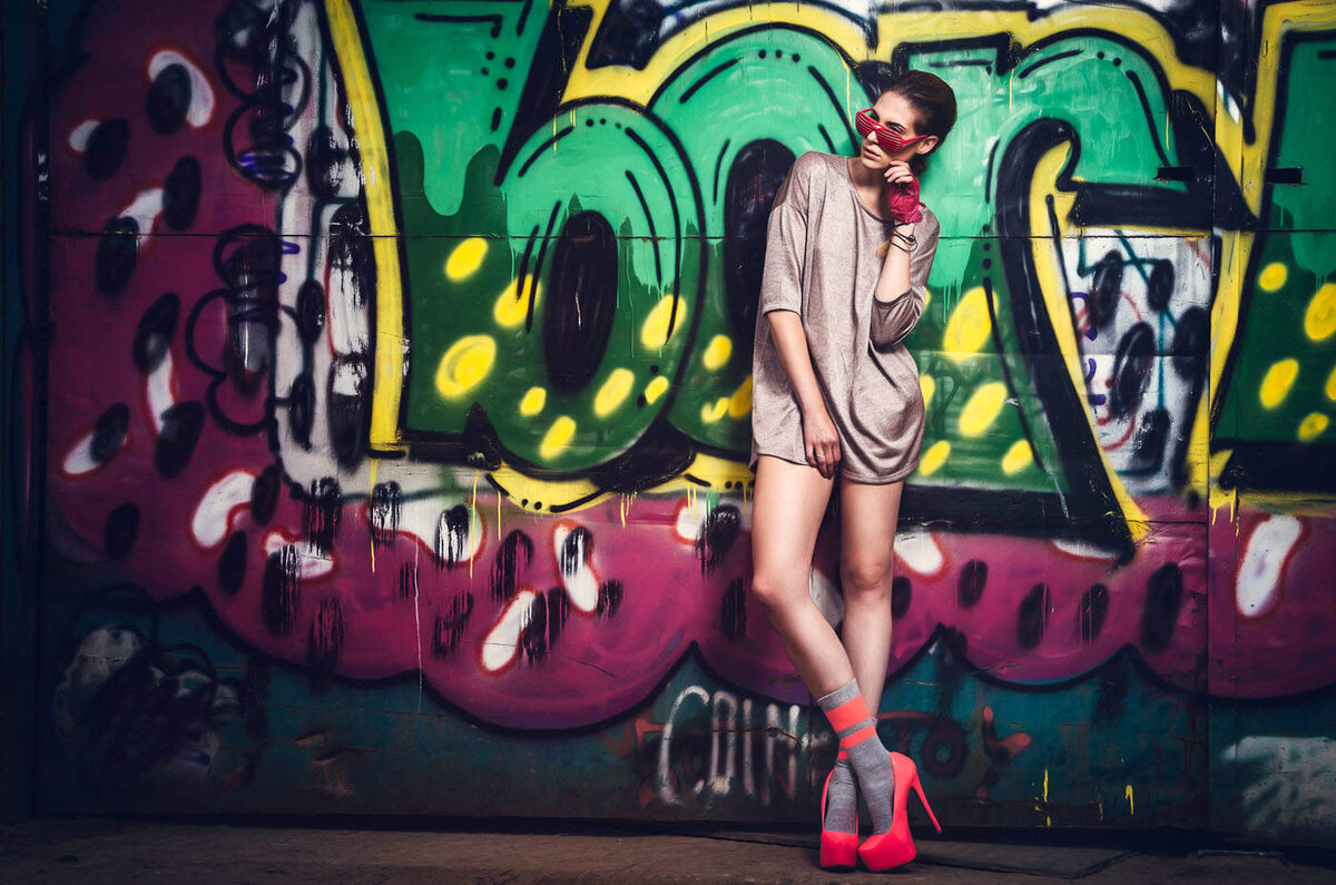 Frau in roten Schuhen vor einer Graffitiwand